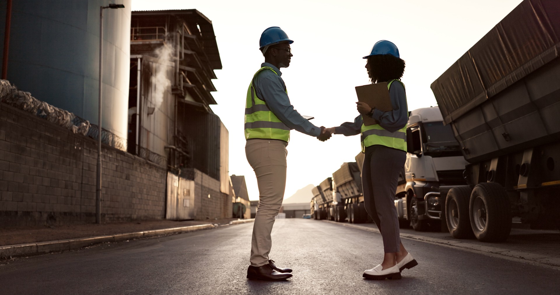 Engineer, handshake and people at construction site for welcome, greeting or agreement on building plan. B2B, contractor man and black woman with clipboard for deal, partnership and collaboration